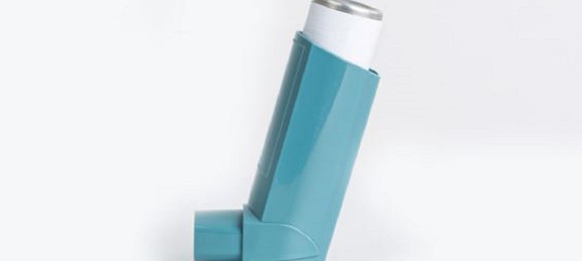 Person using an inhaler for icd-10 code for asthma treatment, managing symptoms and improving breathing.