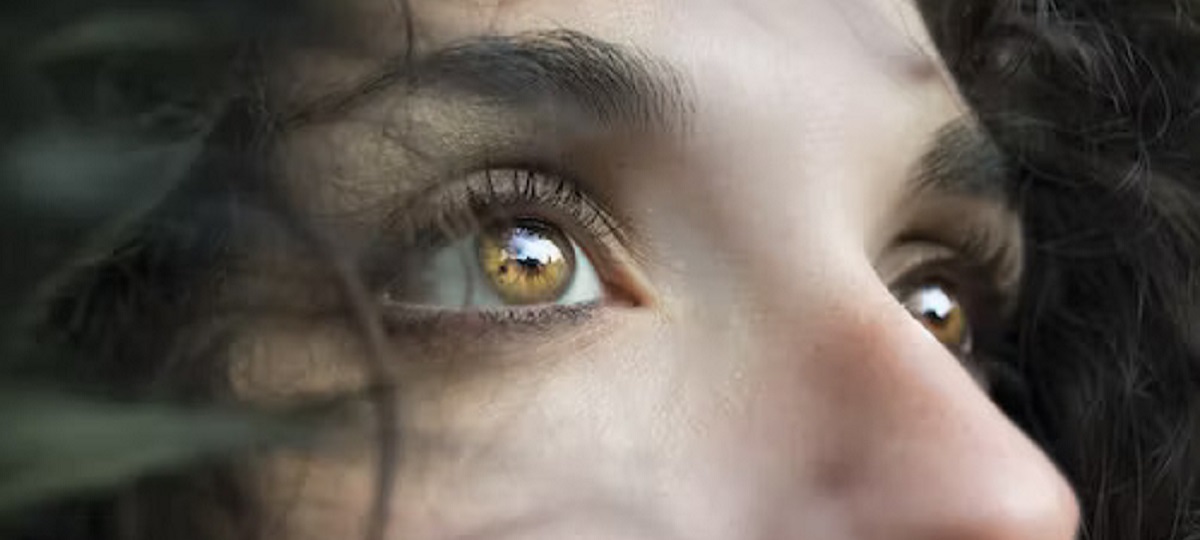 Woman holding a bottle of eye vitamins, promoting relief for dry eyes and better eye health.