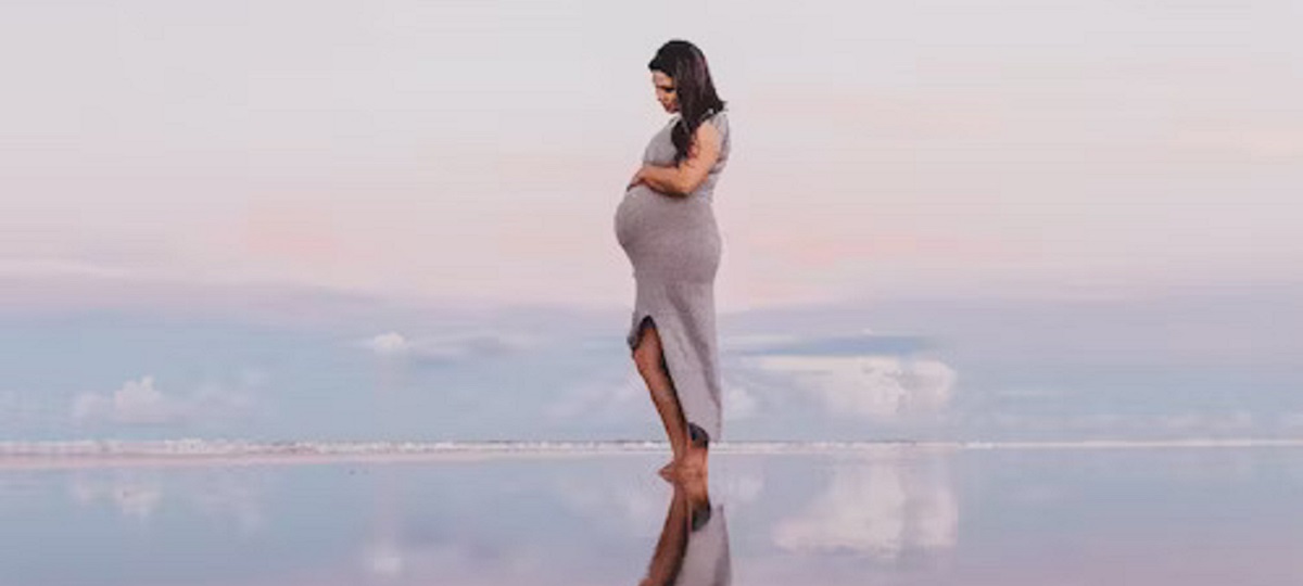 A pregnant woman holding tissues, experiencing pregnancy rhinitis with nasal congestion and runny nose due to hormonal changes.