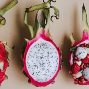 A halved dragon fruit with white flesh and black seeds, showcasing its sweet and refreshing taste.