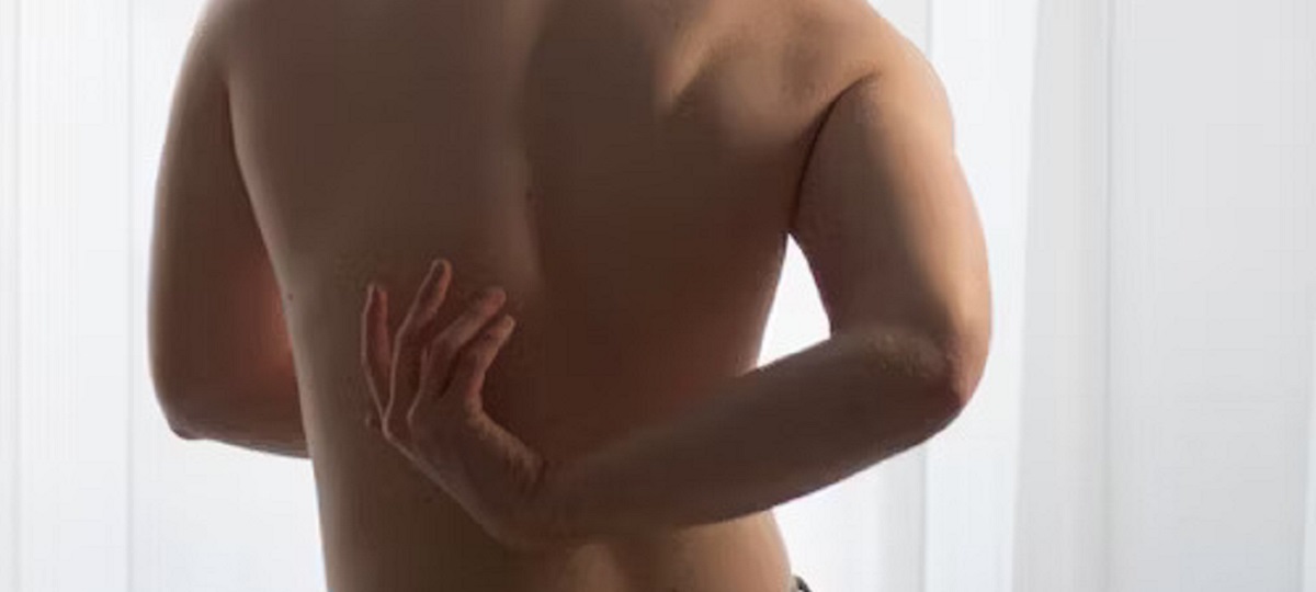 Person experiencing upper back pain between the shoulder blades and seeking relief