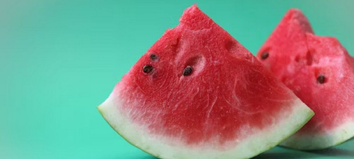 A person's hand holding a slice of fresh watermelon, representing a healthy and balanced approach to managing diabetes through mindful consumption.