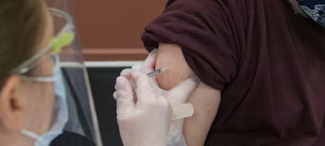 Person receiving a flu shot with a bandage on their arm, representing post-vaccination care precautions.