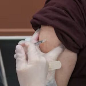 Person receiving a flu shot with a bandage on their arm, representing post-vaccination care precautions.