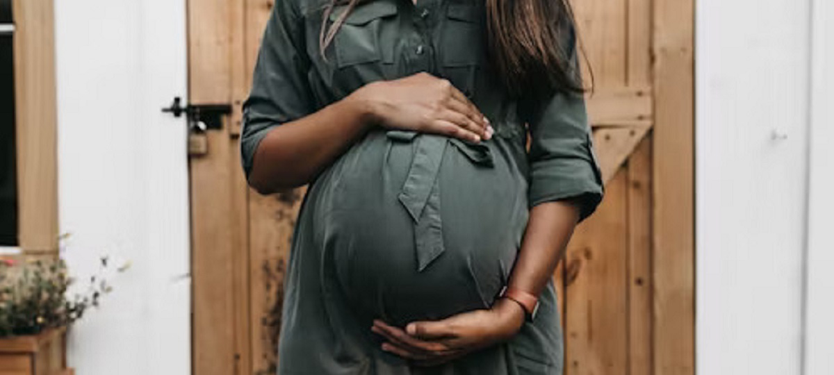 A pregnant woman holding her lower abdomen in discomfort, indicating possible lower right abdominal pain during pregnancy.